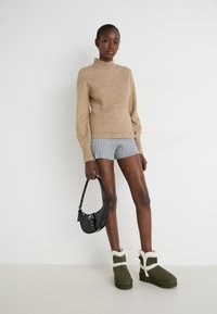 Beige knitted sweater, grey ribbed shorts, olive green boots with white faux fur trim, and a black handbag. Simple, casual outfit.