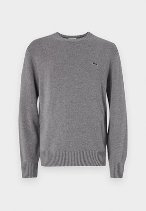 Maglione grigio lavorato a maglia con scollatura rotonda, polsini e orlo a coste, con un piccolo logo di coccodrillo verde sul lato sinistro del petto.