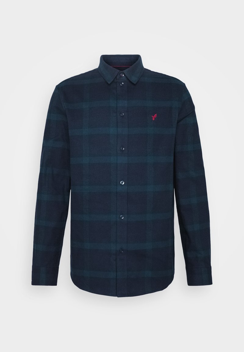Chemise bleue marine pour homme avec boutons, motif à carreaux subtil et petit logo rouge brodé sur la poitrine gauche.
