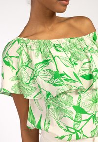 Off-shoulder blouse van lichtgewicht stof, met een groene bloemenprint op een crèmekleurige achtergrond en gelaagde randdetails.
