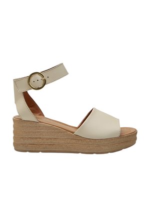 Sandalo beige con zeppa e cinturino alla caviglia con fibbia rotonda dorata e suola platform texturizzata.