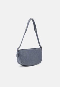 Denim schoudertas in donkerblauw met een gebogen vorm, een gestructureerd oppervlak en een gespikkelde schouderband. Voorzien van een ritssluiting en een zachte voering.