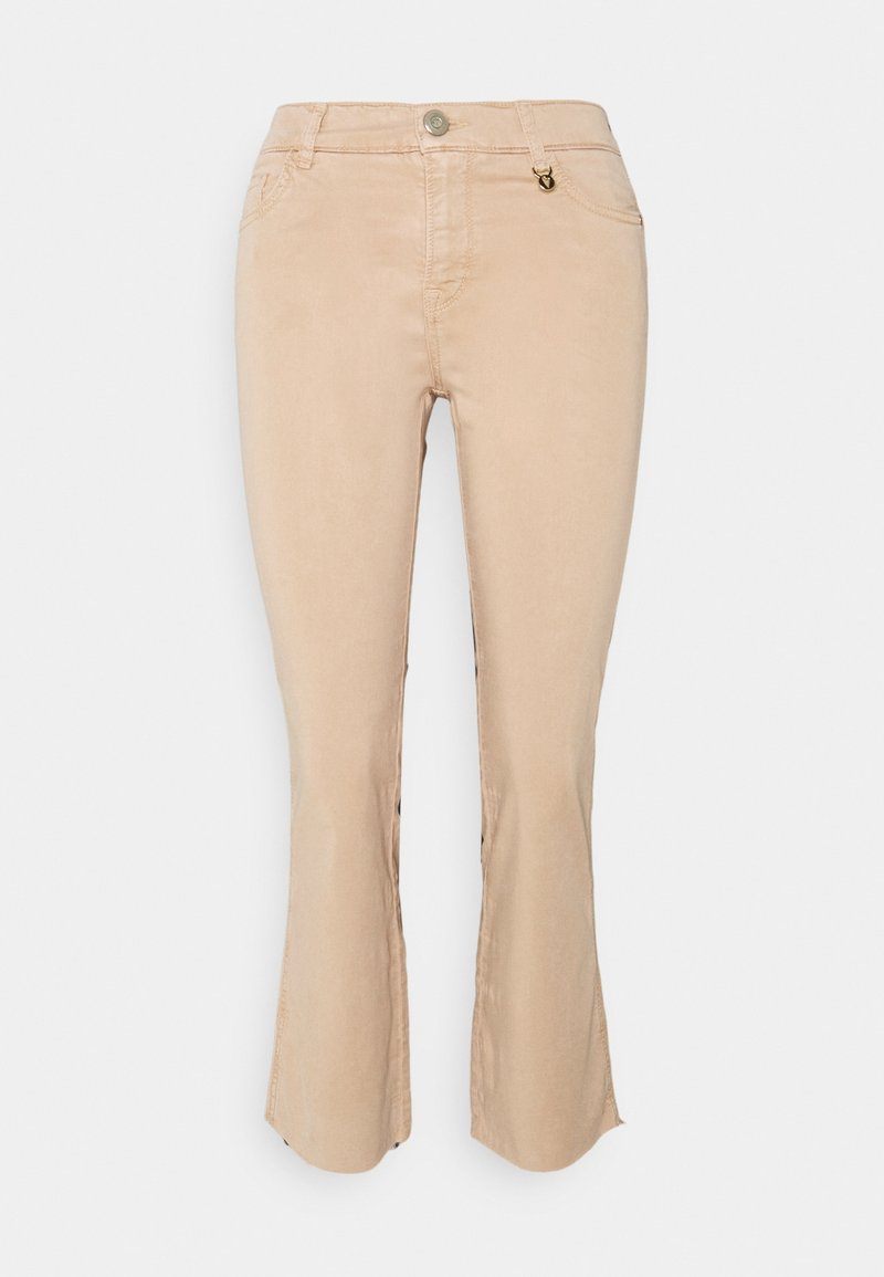 Light beige cropped pants with a slim fit, slight flare at the hem, front pockets, and a small metallic accent on the waistband.