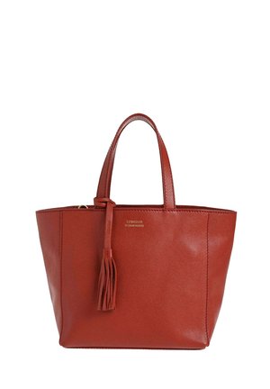 Sac fourre-tout en cuir rouge avec deux poignées et un pompon décoratif suspendu à l'une des poignées.