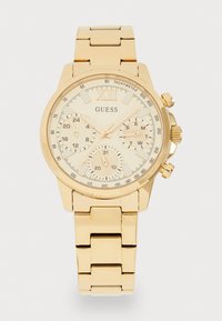 Guld-tone Guess armbåndsur med en rund urskive, tekstureret beige skive, chronograf underurskiver og et poleret metal link armbånd.