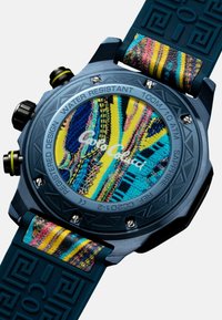 Orologio digitale con cassa in metallo blu, quadrante decorato con motivi colorati, cinturino in gomma nera e dettagli gialli. Resistente all'acqua fino a 100 metri.