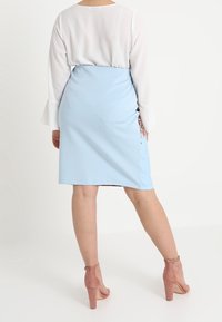 Ljusblå tajt kjol med en sidoklyv, ihop med en vit blus. Outfitten har mjukt tyg och subtila blommönster nära fållen.