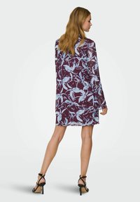 Kerge maroon värvi kleit helesiniste lillede mustriga, pikkade varrukatega ja lõdva istuvusega, koos mustade kõrge kontsaga sandaalidega.