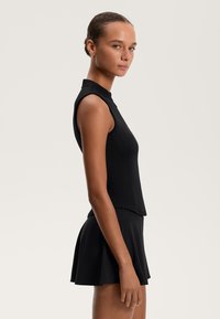 Fekete, ujjatlan felső magas gallérral, amelyhez egy bővülő fekete szoknya párosul. Simább, rugalmas anyag, amely szoros vonalú.