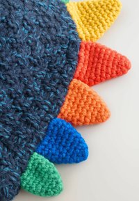 Gehaakt textiel met een donkerblauwe basis en een gestructureerde weving, versierd met kleurrijke puntige accenten: rood, oranje, geel, groen en blauw.