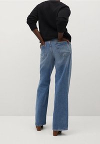 Jean bleu taille haute, coupe décontractée, en denim. Dispose de deux poches arrière et d'un léger effet délavé vers le bas.