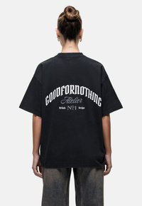 Zwarte oversized T-shirt met de opdruk "GOODFORNOTHING" in het wit op de achterkant, met afgeronde tekst, gemaakt van katoen en een relaxte pasvorm.