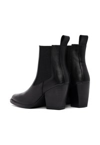 Botas negras de tobillo con un acabado de cuero liso, paneles laterales elásticos y tacones apilados. El diseño presenta una punta redondeada y un detalle mínimo.