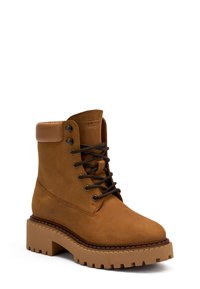 Botas de cuero marrón hasta el tobillo con un collar acolchado, punta redonda y suela de plataforma de goma gruesa y texturizada. Presenta cordones negros y ojales de metal.