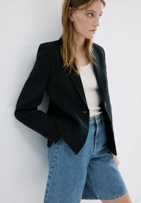 Sacou negru cu dungi fine, umeri structurați, cu doi nasturi. Asortat cu pantaloni scurți din denim cu talie înaltă, de culoare albastru deschis. Material texturat, croială ajustată.