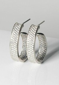 Silverhänge i form av ringar med en texturerad yta prydd med flera klara kristaller, vilket ger en glittrande finish.