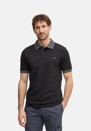 Camisa polo negra con un collar y mangas a rayas grises, con un escote abotonado y un pequeño parche de logo en el pecho.