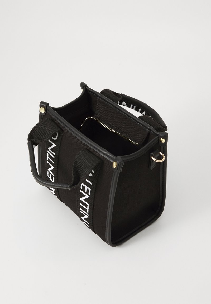 Black fabric handbag with interior zip pocket, sturdy handles, and contrasting white logo straps, designed in a compact rectangular shape.