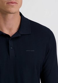Navy-Polohemd mit strukturiertem Fischgrätmuster, Kragen, Knopfleiste und dezentem Logo-Stich auf der Brust.