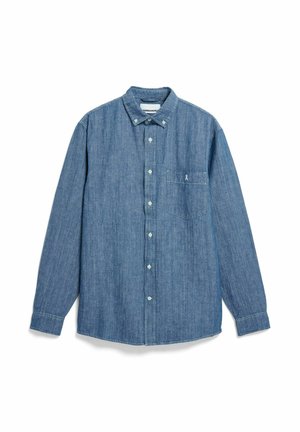 Chemise en denim bleu à manches longues avec col boutonné, poche avant et un petit détail de ruban sur la poche. Boutons blancs.