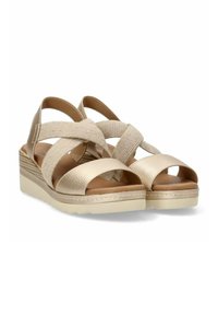 Sandalias de cuña beige con tira frontal de cuero texturizado y tiras cruzadas de tela elástica, punta abierta y suela acolchada.
