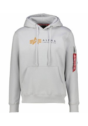 Lysegrå Alpha Industries hættetrøje med frontlomme, snørrehætte, logo i orange og sort samt ærmelomme med lynlås og rødt "Remove Before Flight" mærkat.
