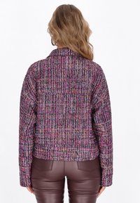 Giacca cropped con un tessuto multicolore e testurizzato caratterizzato da motivi intrecciati in rosa, viola e nero; rifinita con un colletto e maniche lunghe.
