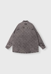 Giacca in denim grigio con un motivo floreale ripetuto, polsini con bottoni, colletto e un'etichetta del marchio visibile sulla parte superiore della schiena.