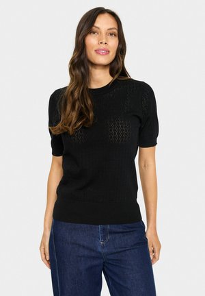 Zwarte sweater met korte mouwen, voorzien van een gestructureerd, opengebreid patroon. Strak model met een ronde halslijn en geribbelde zoom. Gekocht in combinatie met donkerblauwe jeans.