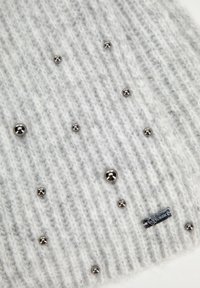 Lichtgrijze gebreide beanie met een ribbelstructuur. Bevat zilveren decoratieve kralen en een klein logo-label, wat de minimalistische uitstraling benadrukt.