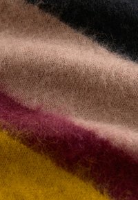 Villane kangas, millel on horisontaalsed triibud mustas, beežis, burgundis ja kollases, pehme, tekstuuriga pind ja karvane välimus.
