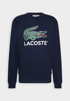 Marineblauwe sweatshirt met lange mouwen, met een groot groen krokodillenlogo en de tekst "LACOSTE" aan de voorkant.