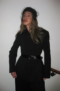 Mustat räätälöidyt takit pitkät hihat ja kuminauhallinen vyötärö, yhdistettynä leveään mustaan vyöhön, jossa on suuri pyöreä solki, ja humpuuki hattu.