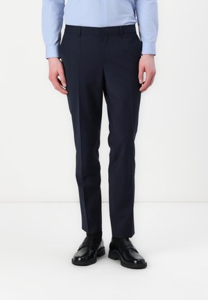 Navy blue trousers with a tailored fit, made from smooth fabric, featuring a flat front and side pockets. Paired with black slip-on shoes.