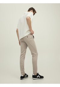 Lichtkleurig shirt met korte mouwen, beige slim-fit broek en zwarte sneakers met witte accenten. Soepele textuur, casual ontwerp.