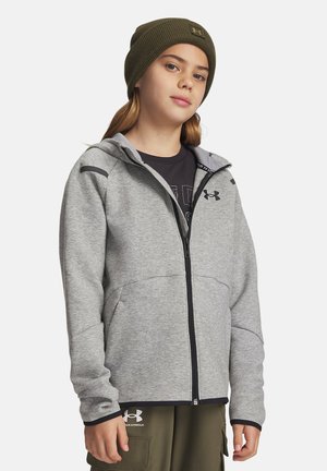 Grauem Reißverschluss-Hoodie mit Kapuze, der dunkle Akzente an den Ärmeln und Taschen hat. Getragen über einem schwarzen T-Shirt, kombiniert mit olivgrünen Hosen.