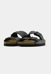 Schwarze Slipper-Sandalen mit zwei verstellbaren Riemen, Korkfußbett und Gummisohle mit strukturiertem Grip. Einfaches und funktionales Design.