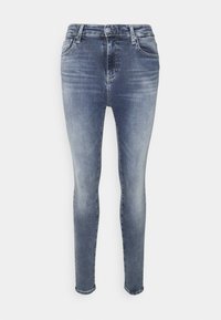 Jeans ajustados en denim azul claro, con un clásico diseño de cinco bolsillos, cierre de cremallera y un sutil desgaste para un efecto usado.