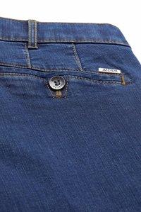 Blue denim trousers featuring contrasting yellow stitching, a metal button closure, and a branded tag on the waistband.