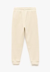 Joggery w fakturze waflowej, jasnobeżowe, z elastycznym paskiem w talii i mankietami, oferujące dopasowany krój i wygodny design.