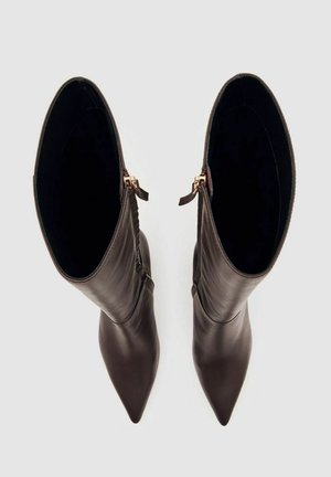 Bruine leren enkellaarsjes met een puntige neus, ritssluiting, een gladde textuur en een strakke uitstraling. Open bovenkanten tonen de binnenkant details.