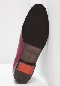 Podešev burgundských kožených společenských bot s černým texturovaným přední částí, hnědým středem s razítkem "MELVIN & HAMILTON 37" a ozdobným emblémem na patě.