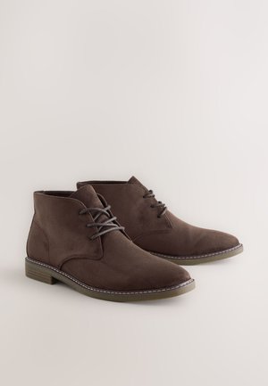 Bottines en daim marron avec un bout arrondi, un design à lacets et des accents de couture contrastants. Talon bloc bas avec une semelle texturée.