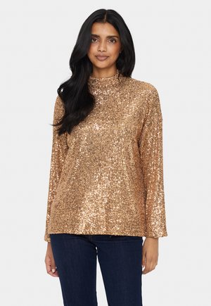 Bronze sequined long-sleeve top with a high neckline and loose fit. Textured surface reflects light, paired with dark denim.