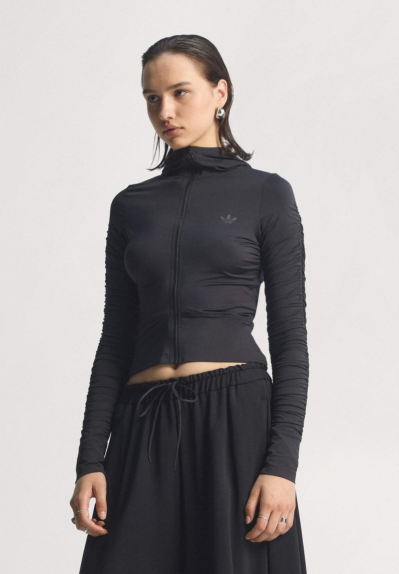 Maglione nero con zip e maniche lunghe, con dettagli arricciati; realizzato in tessuto elasticizzato; presenta un piccolo logo sul petto e un design aderente.