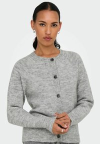 Grå stickad cardigan med rund hals, med knappstängning, ribbade ärmslut och ett strukturerat mönster. Mjukt material med en avslappnad passform.