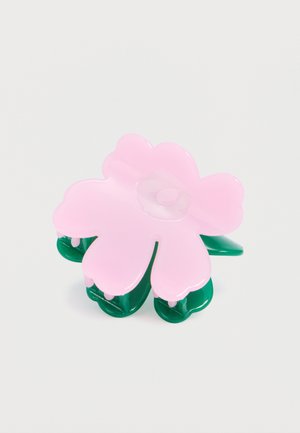 Roosa plastikust lillekujulise klambriga juukseklamber, millel on ümarad kroonlehed ja roheline kinniti, valgel taustal.