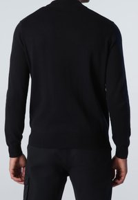 Black knit sweater with long sleeves, round neckline, and ribbed hem and cuffs. Smooth texture and fitted design.