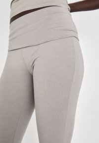Light gray leggings made of soft, stretchy material. Features a wide waistband and smooth texture, with a fitted silhouette and no visible patterns.