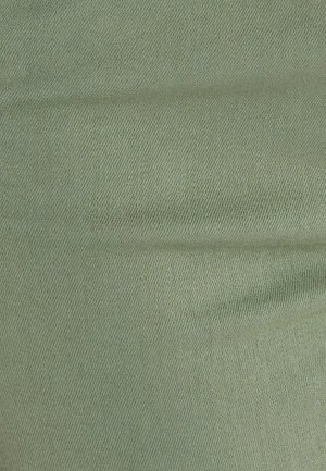 Lichtgroene stof met een textuur, geweven patroon. Het materiaal heeft een zachte uitstraling en een iets gedempte kleurtint.